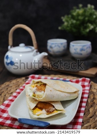fish snack wrap. white fish crispy, lettuce, shredded cheddar jack cheese, Monterey Jack cheese, and sauce (ranch, honey mustard or salsa roja), wrapped in a soft flour tortilla. selective focus