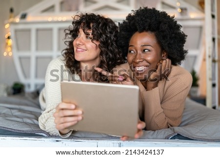 Happy gay couple looking at digital tablet together at home