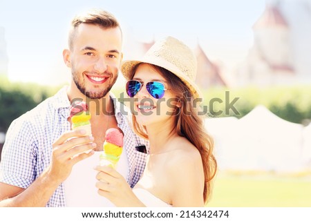 A picture of a joyful couple eating ice-cream cones in the city