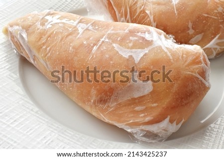 Frozen chicken breast in food plastic wrap.  Photo can be used for how to wrap meat for freezer concept.  Royalty-Free Stock Photo #2143425237