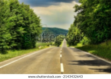 Asphalt road in highland surrounded by green trees with beautiful panorama in blurry view
