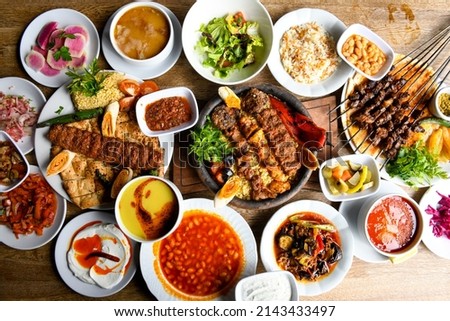 Delicious meat kebab with fresh vegetable salad served with variety of Turkish dishes and appetizers. Top view of assorted Turkish food and meze, tasty and healthy Mediterranean cuisine. Royalty-Free Stock Photo #2143433497