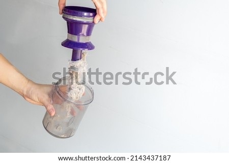 Asian woman's hand is opening a dust mite filter to reveal the dirt. Royalty-Free Stock Photo #2143437187