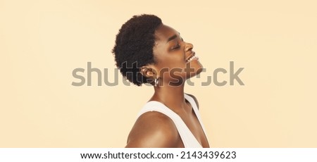 Beautiful black woman . Beauty portrait of african american woman with clean healthy skin on beige background. Smiling beautiful afro girl.Curly black hair 