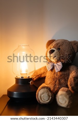 Teddy bear toy for children and party lamp with warm light. Atmosphere before going to bed.