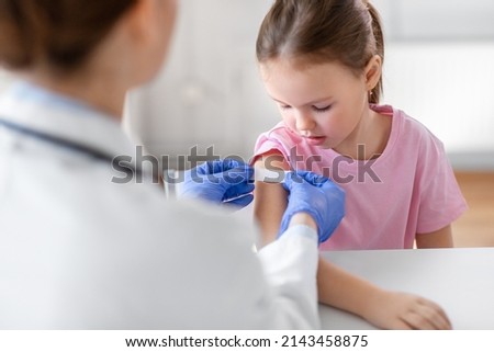 medicine, healthcare and vaccination concept - female doctor or pediatrician talking to little girl patient on medical exam at clinic Royalty-Free Stock Photo #2143458875