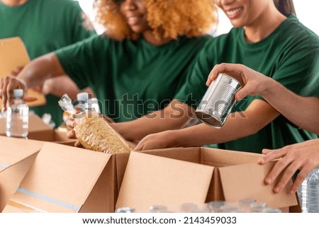 charity, donation and volunteering concept - close up of international group of happy smiling volunteers packing food in boxes at distribution or refugee assistance center Royalty-Free Stock Photo #2143459033