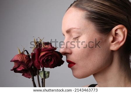 Beauty close-up portrait of young caucasian woman with dry flower rose. Isolates on white background.