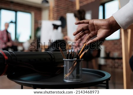 Close up of student hand taking graphic pencils in creativity studio. In background multi ethnic team drawing vase sketch on white canvas working at sketching technique. New years resolutions Royalty-Free Stock Photo #2143468973