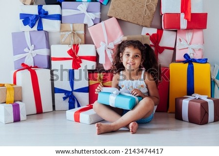 curly little girl opens gifts for the holiday