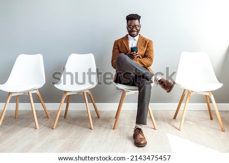Studio shot of a young businessman using a smartphone while waiting. He's got his prep notes in digital format. He was singled out for the job! 