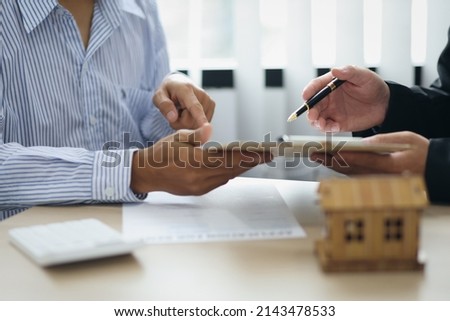 Real estate agent discussing about the terms of the purchase agreement and sign the documents to make the contract legally. Home sales, renting, leasing, mortgage and home insurance concept.