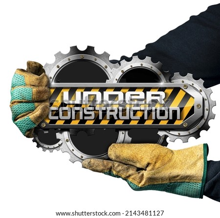 Gloved hand holding an under construction sign with metal cogwheels (gears), isolated on white background.
