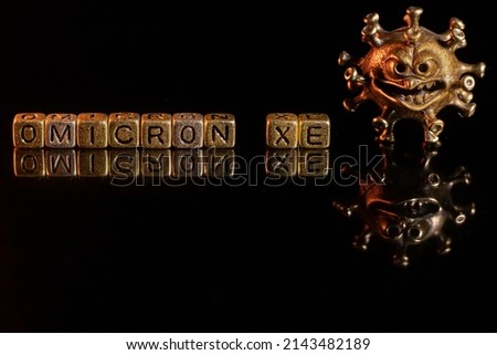 XE. A new variant of SARS-CoV-2 coronavirus. Omicron sub variant. Viral gold color on a black background Royalty-Free Stock Photo #2143482189