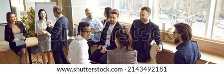 Happy people standing in modern office and talking. Multiracial group of men and women discussing team training workshop they have just attended. Employees having break during business seminar