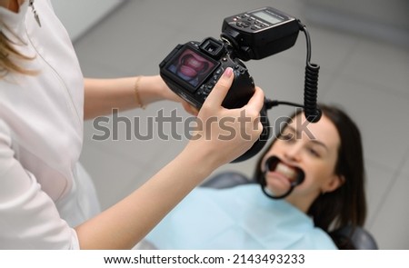 Dentist at work, dental clinic. Young woman doctor taking pictures of patient's teeth and jaw after successful treatment