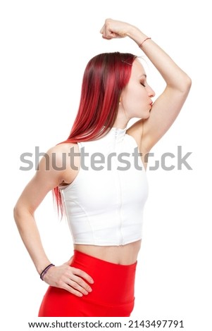 A beautiful, athletic, slim, smiling and cheerful woman in a white top and red sweatpants in a comic form demonstrates a muscular biceps of her hand and kisses it. Lifestyle concept with sports and