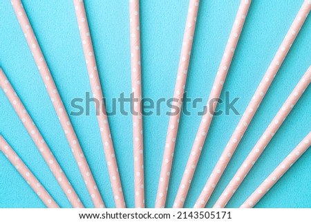 Biodegradable spotted pink paper straw set on blue table background, design concept of environmental protection for Earth Day.