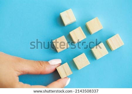 Business concept, hand places wooden cubes on blue background