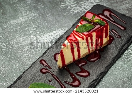 Piece of cheesecake with fresh strawberries jam and mint. Tasty homemade cheesecake on a dark background. Royalty-Free Stock Photo #2143520021