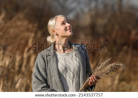 Beautiful woman walks in the autumn park. Happy woman walks in the forest in early spring. Girl in a coat close-up.