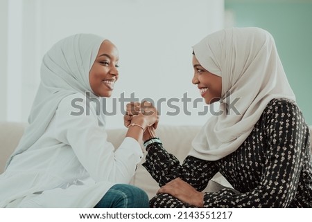 African woman arm wrestling conflict concept, disagreement and confrontation wearing traditional islamic hijab clothes. Selective focus 