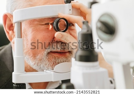 examination of elderly man with slit lamp. microscope and focused light source. device for high-precision examination of eye to determine condition of lens, cornea. medical equipment. Royalty-Free Stock Photo #2143552821