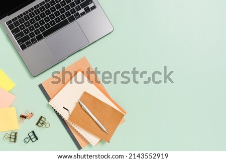 Creative flat lay photo of workspace desk. Top view office desk with laptop, coffee cup and open mockup black notebook on pastel green color background. Top view mock up with copy space photography.