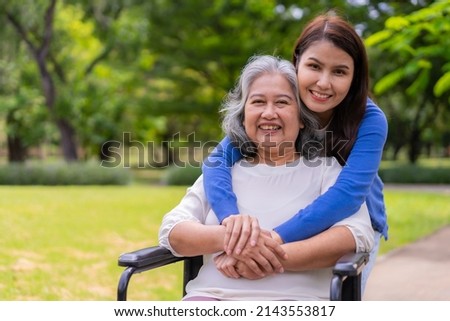 Asian careful caregiver or nurse taking care of the patient in a wheelchair.  Concept of happy retirement with care from a caregiver and Savings and senior health insurance, a Happy family Royalty-Free Stock Photo #2143553817