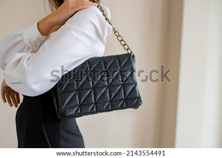 Trendy outfit woman with black bag. Girl with bag over his shoulder outdoors. Shoulder Bags for Women. Fashion look woman outfit. Stylish women's beige handbag. Close-up. Royalty-Free Stock Photo #2143554491