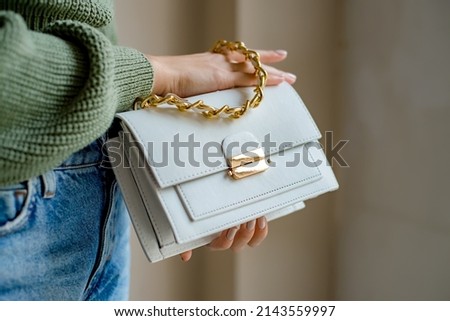 Trendy outfit woman with black bag. Girl with bag over his shoulder outdoors. Shoulder Bags for Women. Fashion look woman outfit. Stylish women's beige handbag. Close-up. Royalty-Free Stock Photo #2143559997