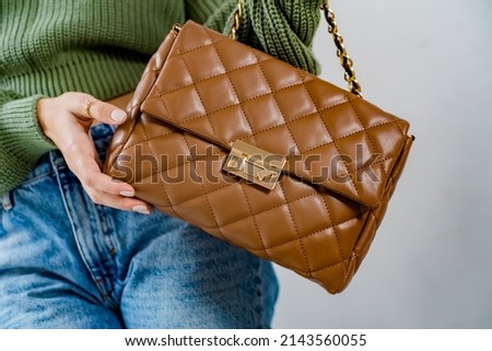 Stylish women's brown handbag. Trendy outfit woman with brown bag. Girl with bag over his shoulder outdoors. Shoulder Bags for Women. Fashion look woman outfit. Close-up. Royalty-Free Stock Photo #2143560055