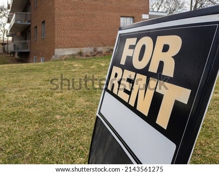Old weathered sign for rent in front of a residential low rise building. Investment property, affordable housing, real estate crisis concept.