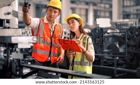 Engineer wearing safety vest controlling machine working talking with assistant engineer worker checking safety first for labour workers. Safety officer check machine in factory. Royalty-Free Stock Photo #2143563125