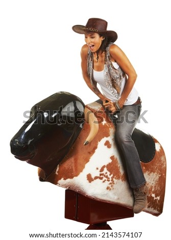 Woah. Studio shot of a beautiful young woman riding a mechanical bull against a white background. Royalty-Free Stock Photo #2143574107