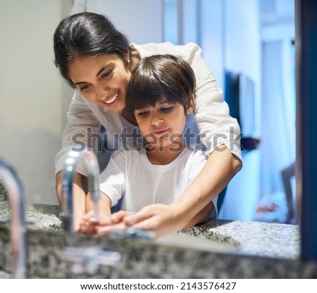 Teaching her son about the practices of good hygiene. Shot of a mother helping her little son wash his hands in the bathroom. Royalty-Free Stock Photo #2143576427