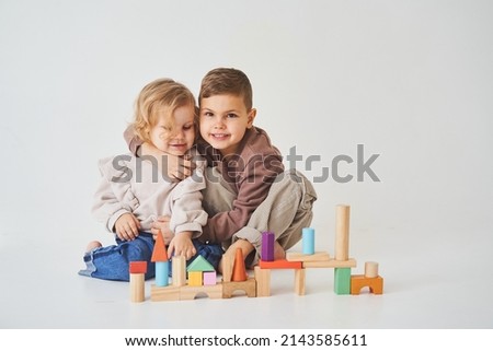 Boy and girl smiling, having fun and playing colored bricks toy on white background. Children have smiling and have fun together