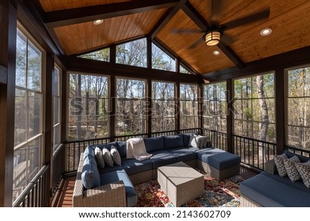 Cozy screened porch in springtime, full of blooms trees in the background.