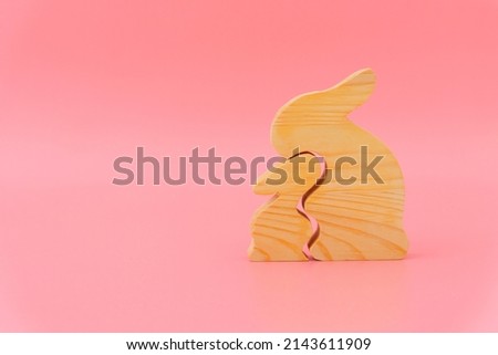 Wooden big and small rabbit. Pink background. Mother's day concept, parental relationship, love, family. Place for text. Greeting card.