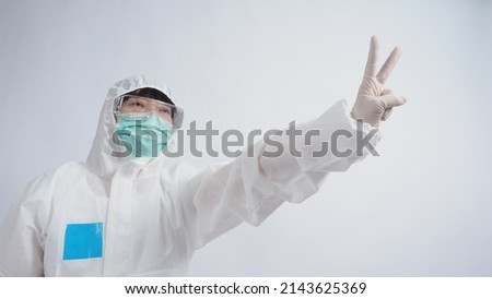 Doctor in PPE suit wearing white medical rubber gloves and clear goggles and green N95 face mask to protect pandemic Coronavirus. gesture make hand sign. Represent victory win over virus. Isolated.