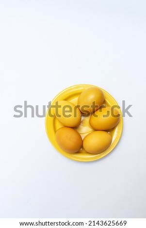 Yellow Easter eggs on a yellow plate and on a white background, copy space