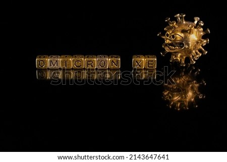 XE. A new variant of SARS-CoV-2 coronavirus. Omicron sub variant. Viral gold color on a black background Royalty-Free Stock Photo #2143647641