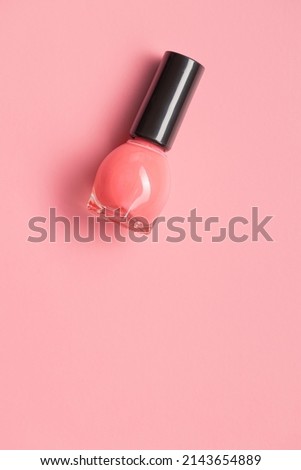 Colorful nail polish bottles on a pink background. Top view.