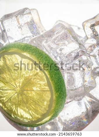 Backlit drink glass, with lime slice, ice cubes, and clear liquid.