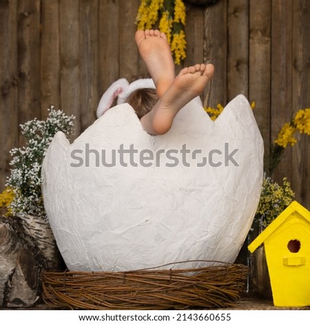 Easter concept. Children's legs protrude from a huge eggshell. A funny and cute Easter picture. Easter background
