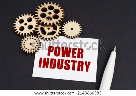 Industrial concept. On the black surface are gears, a pen and a business card with the inscription - Power Industry