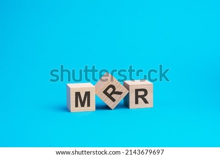 wooden cubes with letters MRR, blue background, business concept. MRR - short for Monthly Recurring Revenue