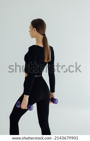Sporty woman doing exercises, making direct hit with dumbbells. Photo of muscular female wearing sportswear on white background. Strength and motivation