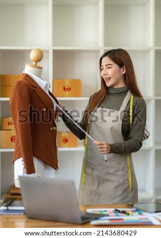 Successful fashion designer. Full length of attractive young asian woman looking at camera with smile while standing in workshop. Beautiful owner business woman working in studio .