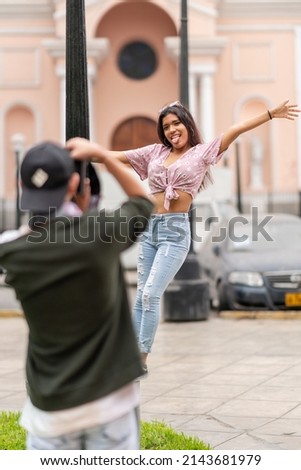 Woman on a lamppost posing while grimacing in front of a friend taking photos of her outdoors